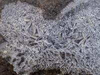 Stäbchenförmige Eisoberfläche auf Wasserpfütze am Weg